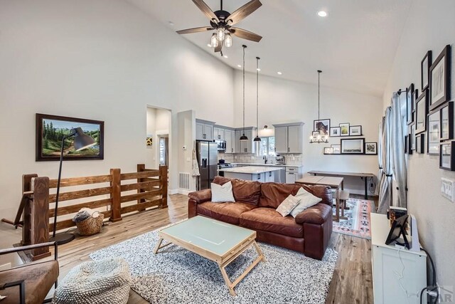 living area featuring ceiling fan, high vaulted ceiling, recessed lighting, visible vents, and light wood-type flooring