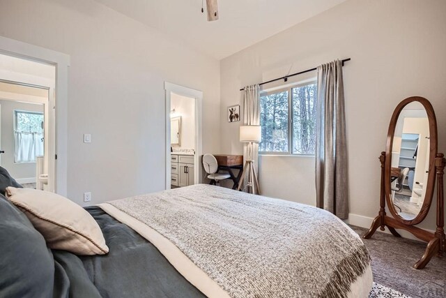 bedroom with carpet, connected bathroom, lofted ceiling, and baseboards