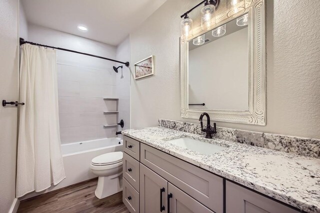 bathroom featuring toilet, vanity, shower / tub combo with curtain, and wood finished floors