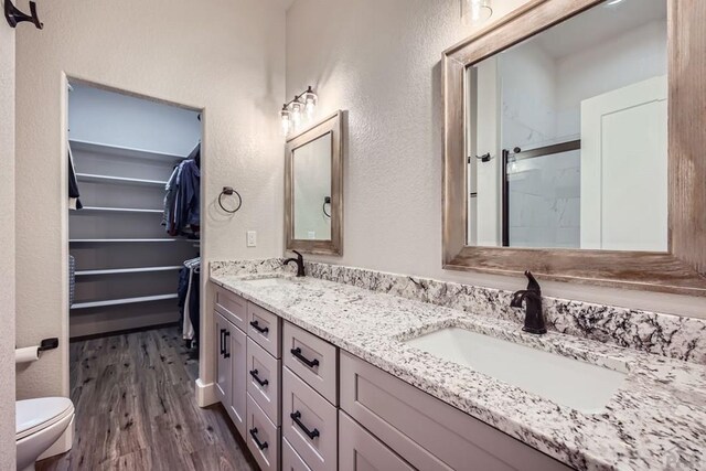 bathroom with a stall shower, a walk in closet, a sink, and wood finished floors