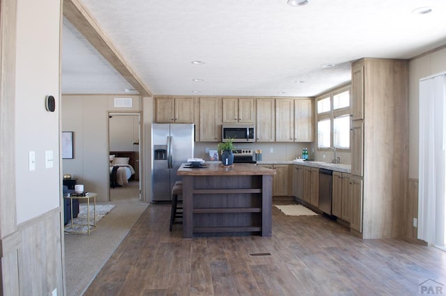 kitchen featuring a center island, open shelves, stainless steel appliances, light countertops, and a sink