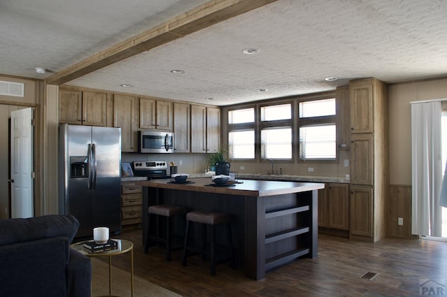 kitchen with light countertops, appliances with stainless steel finishes, a center island, open shelves, and dark wood finished floors