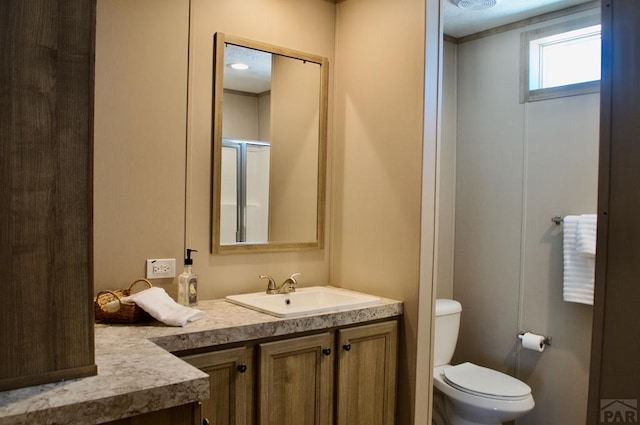 bathroom with toilet, a shower with door, and vanity