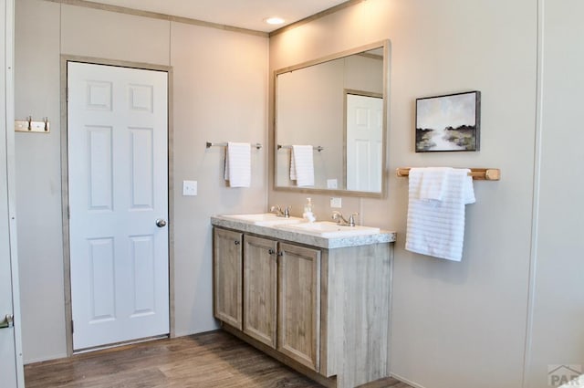 full bath with double vanity, a sink, and wood finished floors