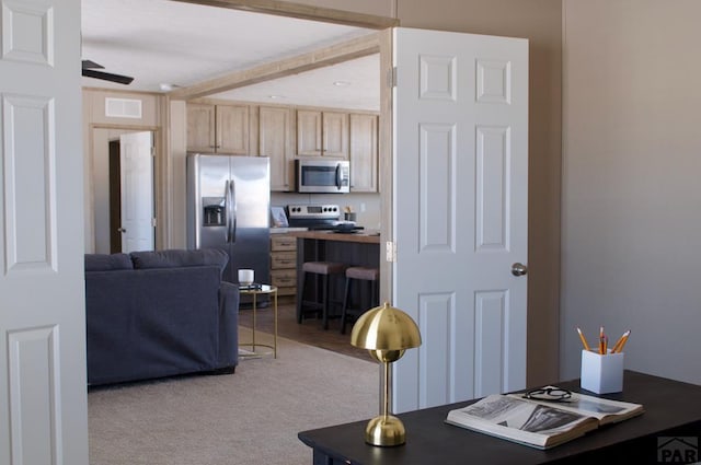 interior space featuring visible vents, light colored carpet, appliances with stainless steel finishes, open floor plan, and light brown cabinetry