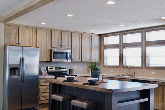 kitchen featuring stainless steel appliances, a sink, light countertops, a center island, and open shelves