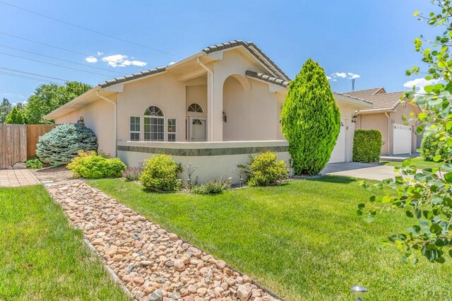 view of front of house with stucco siding, a tiled roof, an attached garage, fence, and a front yard