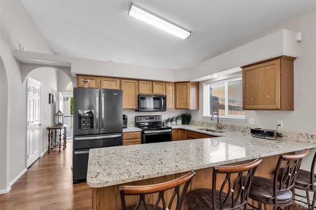 kitchen featuring brown cabinetry, electric stove, a peninsula, black refrigerator with ice dispenser, and a sink