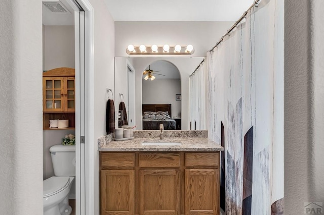 bathroom with visible vents, toilet, a ceiling fan, vanity, and ensuite bath