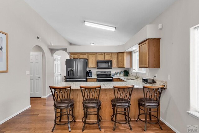 kitchen with a sink, visible vents, fridge with ice dispenser, range, and brown cabinets