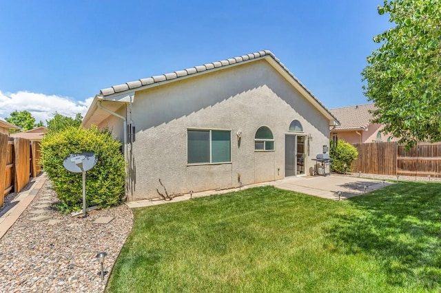 back of property featuring a fenced backyard, a patio, a lawn, and stucco siding