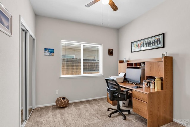 office area with light carpet, a ceiling fan, and baseboards