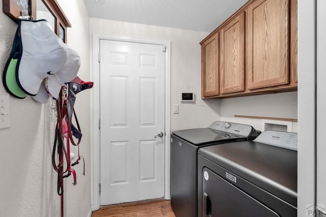 laundry room with cabinet space, light wood-style flooring, and separate washer and dryer