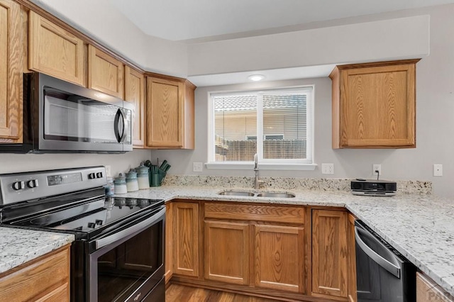 kitchen with stainless steel appliances, a sink, and light stone countertops