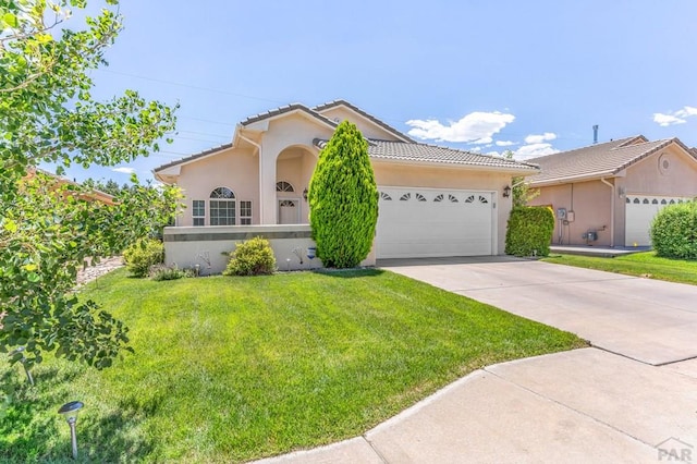 view of front of home with driveway, a tiled roof, a front lawn, and stucco siding