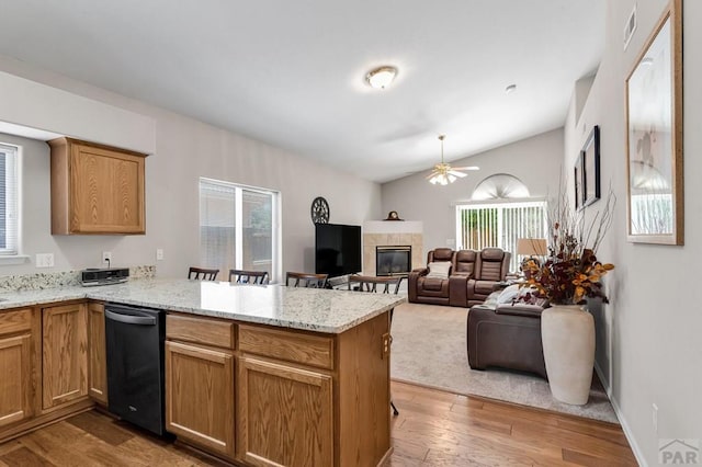 kitchen with open floor plan, wood finished floors, a peninsula, vaulted ceiling, and a fireplace