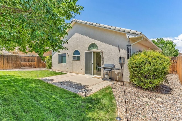 back of house with a patio, a lawn, a fenced backyard, and stucco siding