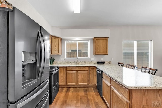 kitchen featuring electric stove, a breakfast bar area, a sink, a peninsula, and stainless steel fridge with ice dispenser