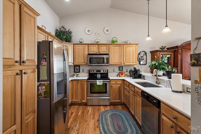 kitchen featuring light countertops, hanging light fixtures, appliances with stainless steel finishes, a sink, and high vaulted ceiling