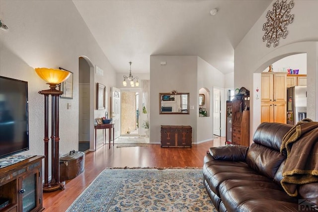 living area with arched walkways, wood finished floors, and lofted ceiling