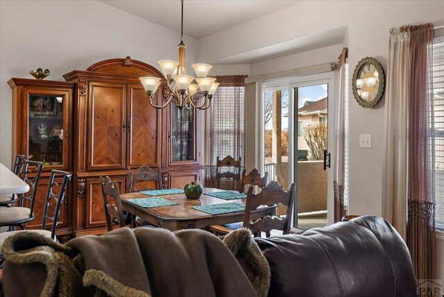 dining space with lofted ceiling and an inviting chandelier