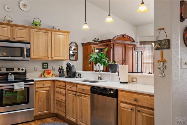 kitchen featuring light countertops, appliances with stainless steel finishes, hanging light fixtures, and a sink