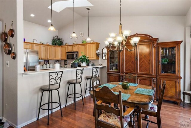 dining area featuring a chandelier, high vaulted ceiling, wood finished floors, and recessed lighting