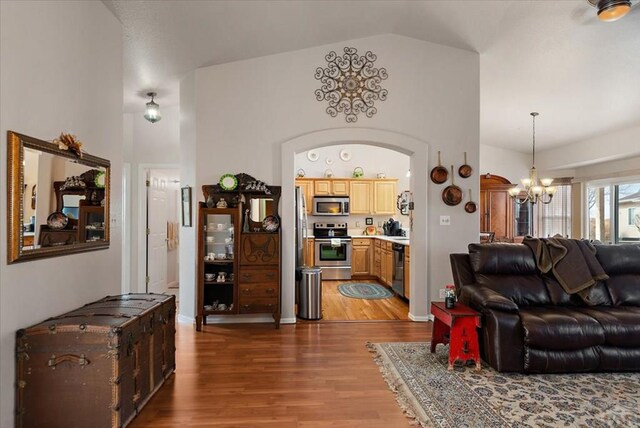 living room featuring arched walkways, high vaulted ceiling, wood finished floors, and a chandelier