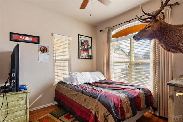 bedroom with ceiling fan, dark wood finished floors, and baseboards