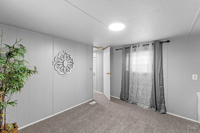 carpeted spare room with a textured ceiling and visible vents