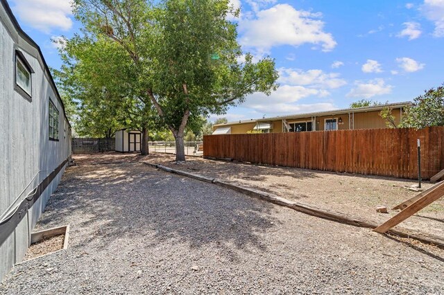 view of yard featuring an outbuilding, a fenced backyard, and a storage shed