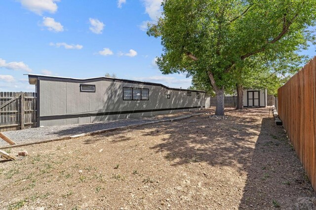 rear view of property with a storage shed, an outdoor structure, and a fenced backyard