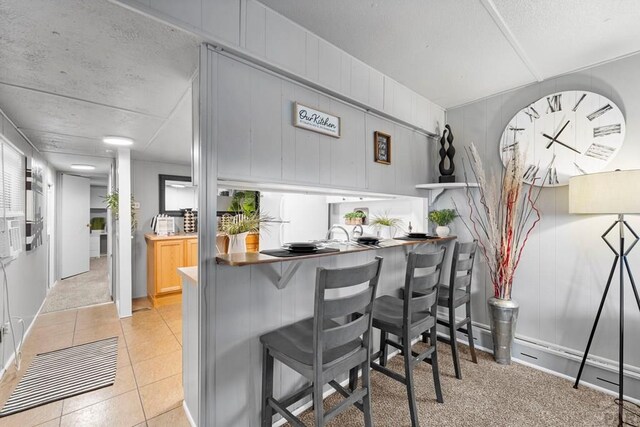 kitchen with light tile patterned floors, light brown cabinetry, a peninsula, and a kitchen breakfast bar