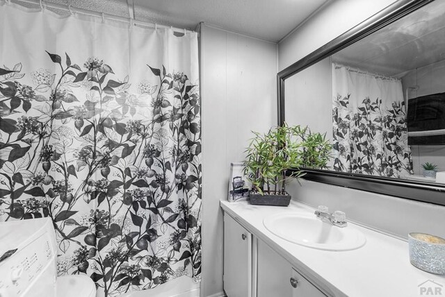 bathroom featuring toilet, washer / dryer, a shower with curtain, and vanity