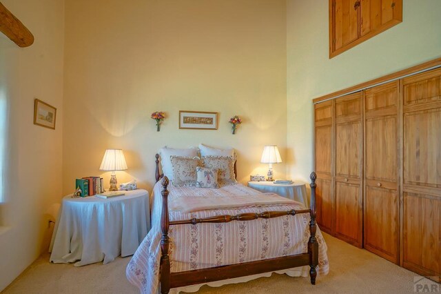 bedroom with a towering ceiling and light colored carpet