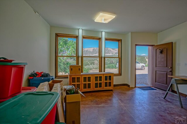 recreation room featuring finished concrete flooring, a mountain view, and baseboards