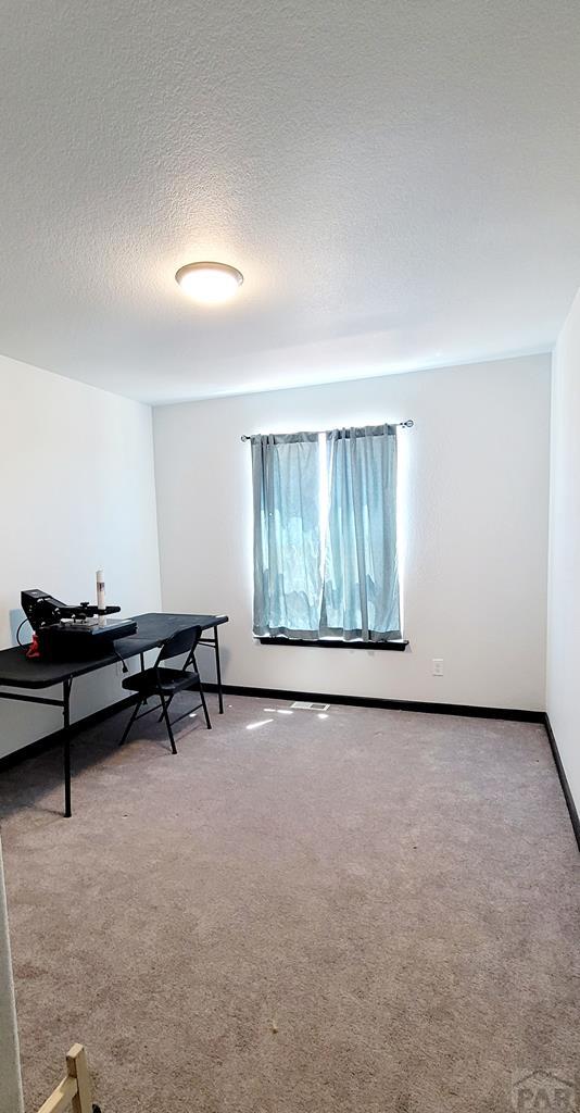 recreation room with a textured ceiling, carpet floors, and baseboards