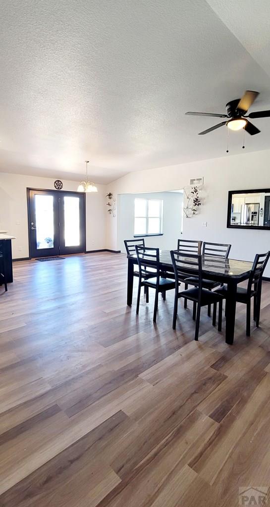 dining space featuring a ceiling fan, french doors, a textured ceiling, and wood finished floors