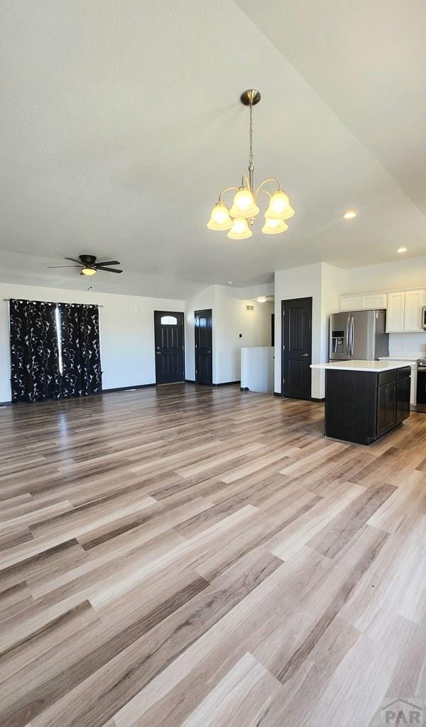 unfurnished living room featuring recessed lighting, light wood finished floors, and ceiling fan with notable chandelier