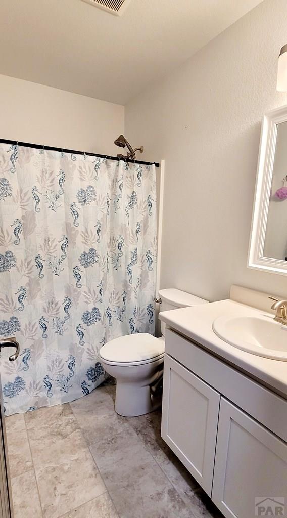 full bath featuring toilet, a shower with curtain, visible vents, and vanity