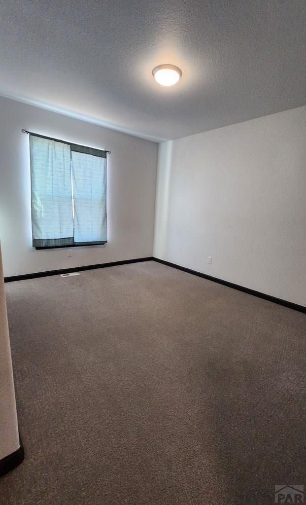 empty room with baseboards, a textured ceiling, and carpet flooring