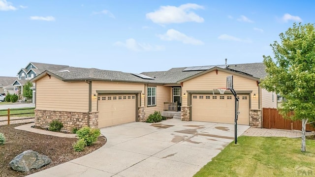 view of front of home featuring a garage, stone siding, fence, and solar panels