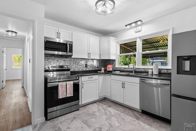 1121 Alexander Cir, Pueblo, CO 81001 - kitchen with appliances with stainless steel finishes, a sink, decorative backsplash, dark countertops, and white cabinets