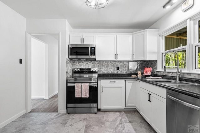 1121 Alexander Cir, Pueblo, CO 81001 - kitchen with stainless steel appliances, a sink, decorative backsplash, white cabinetry, and baseboards