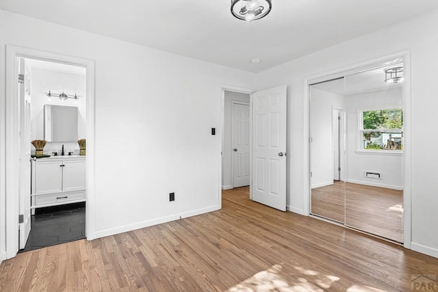 1121 Alexander Cir, Pueblo, CO 81001 - unfurnished bedroom featuring light wood-style flooring, a sink, baseboards, ensuite bathroom, and a closet