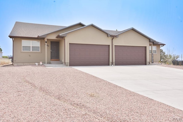 ranch-style house with a garage, concrete driveway, and stucco siding