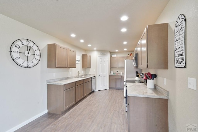 kitchen with light wood finished floors, recessed lighting, a sink, light stone countertops, and baseboards