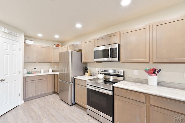 kitchen with light wood finished floors, light stone countertops, stainless steel appliances, light brown cabinets, and recessed lighting