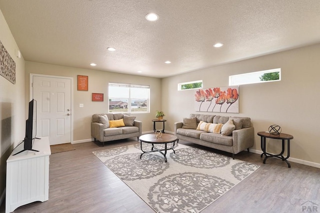 living area with a textured ceiling, baseboards, wood finished floors, and recessed lighting