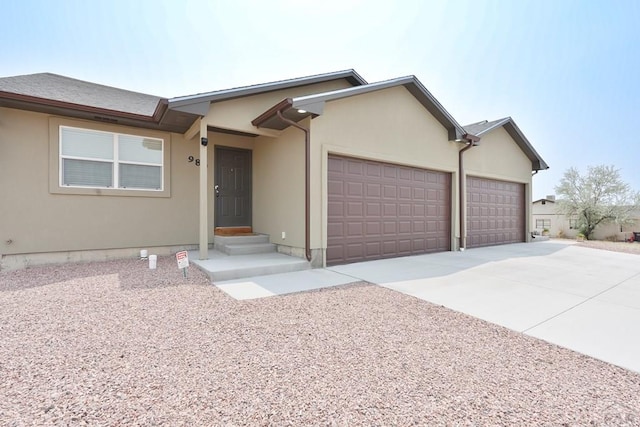 ranch-style house with driveway, an attached garage, and stucco siding